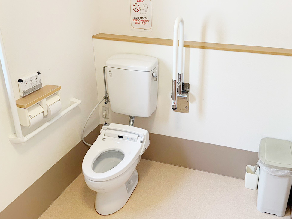 清潔で機能的なトイレ空間。温水洗浄便座と手すり、注意書き掲示。